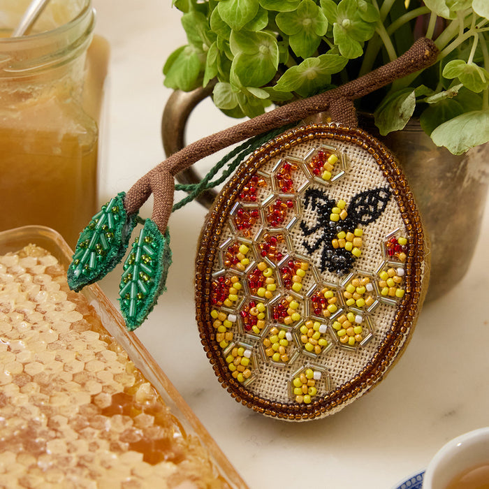 Hand-embroidered beehive ornament with beaded honeybee and shimmering honeycomb