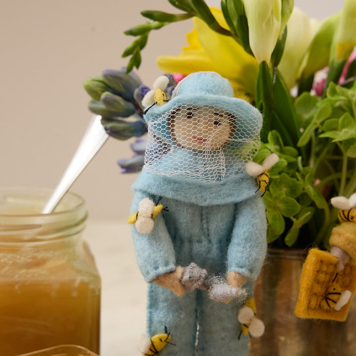 Blue-clad felt beekeeper ornament with fair skin tone and brown hair, ready to hang