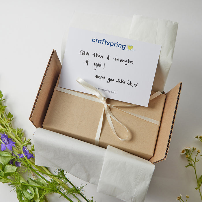 Kraft box tied with a bow packed in a shipping box with a gift card
