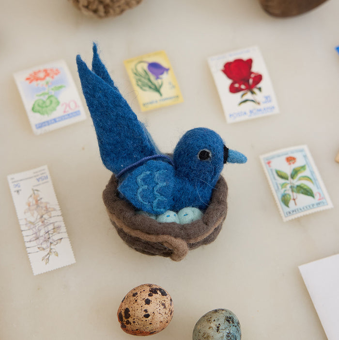 Hand-felted Mama Bluebird ornament warming eggs in a wool nest – spring decor inspired by nature and motherhood.