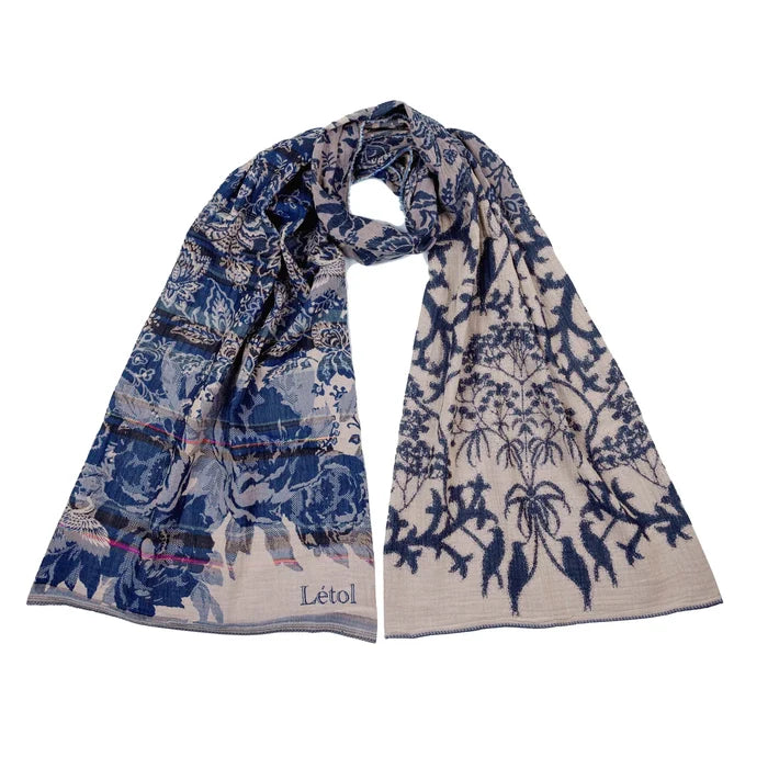 Létol Bridget Scarf in Marine, looped and laid flat against a white background showing both sides simultaneously — one side featuring a bold navy and indigo dense floral and paisley tapestry with large peony and chrysanthemum blooms on a deep blue ground, the other showing an intricate navy tree-of-life and botanical vine pattern on an off-white ground with a large palm and crane motif — with the woven Létol label visible at the lower left and a pink accent selvedge at the center