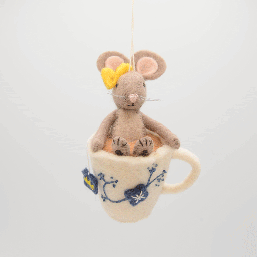 Hand-felted wool ornament of a small gray mouse with a bow, sitting inside a floral teacup with embroidered details. Crafted from merino-blend wool, this whimsical piece evokes tea time and childhood storytelling. Includes a hanging string and measures approximately 4.5 inches tall. A sweet and cozy decoration for tea lovers and mouse enthusiasts alike. GIF 360 degree view.
