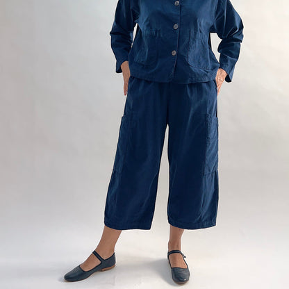 Model with hands in hip pockets of the Bryn Walker Corduroy Pasha Pants in Nova, front view showing relaxed wide-leg silhouette, side leg pockets, and navy pinwheel corduroy texture, with black Mary Jane flats