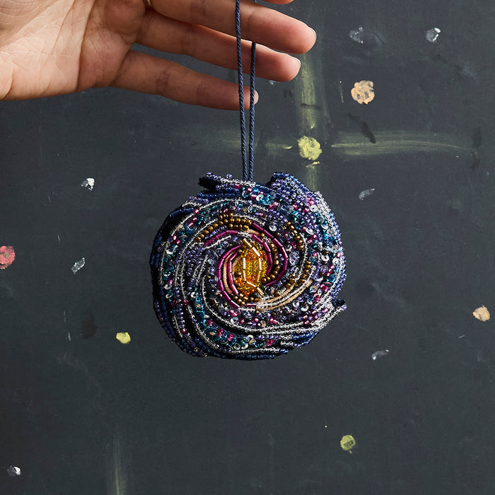 Beaded galaxy Christmas ornament featuring spiral Milky Way design with detailed embroidery. Handmade satin decoration for stargazers and space lovers.