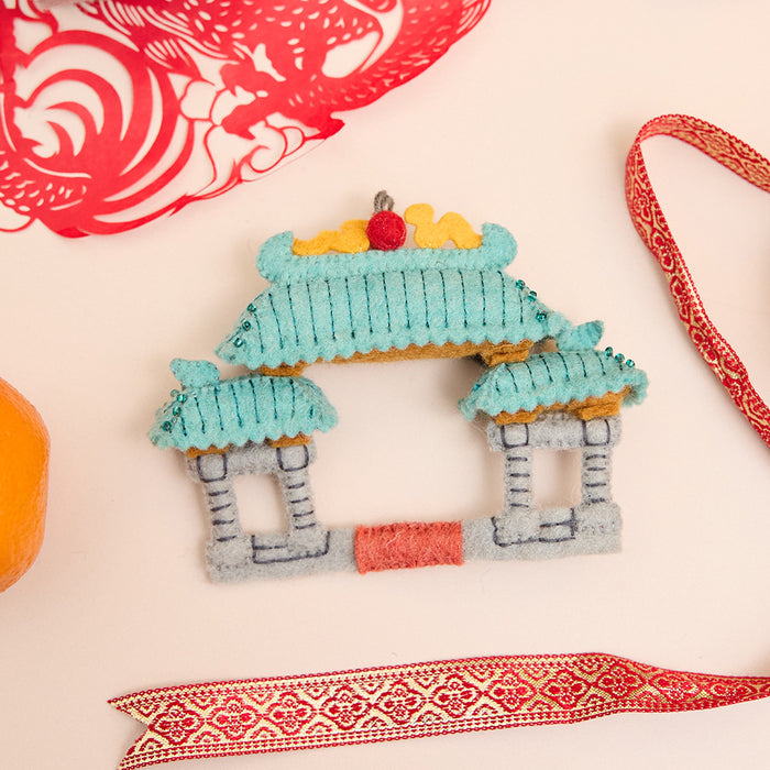 Hand-felted Chinatown Gate ornament with embroidered dragons, jade roof, and vermillion pillars inspired by Chinese architecture. Handmade and fair trade.
